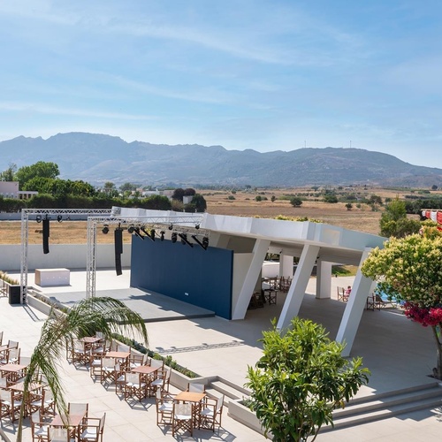 a large outdoor area with tables and chairs and mountains in the background