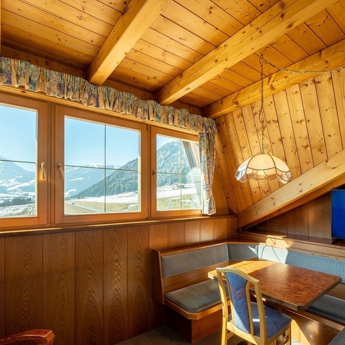 a room with a table and chairs and a tv that says smy koflerhof