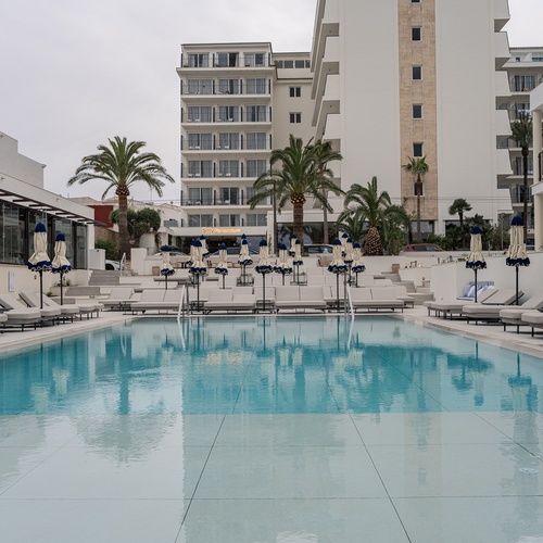 Piscina Smy: Corporativa e espreguiçadeiras com palmeiras e hotel moderno.