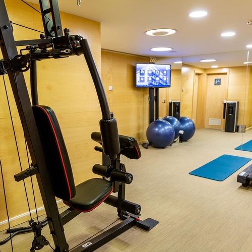 a gym with a treadmill and a tv on the wall