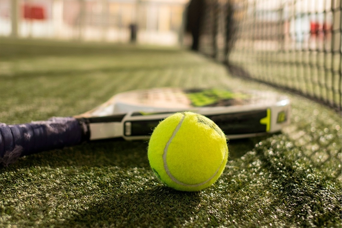 a glass of red liquid with a straw on the beach