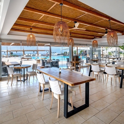 ein Restaurant mit vielen Tischen und Stühlen und einem Pool im Hintergrund