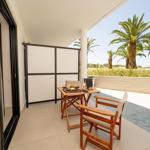 a balcony with a table and chairs and palm trees in the background