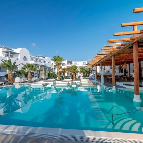 une grande piscine entourée de bâtiments blancs et de palmiers