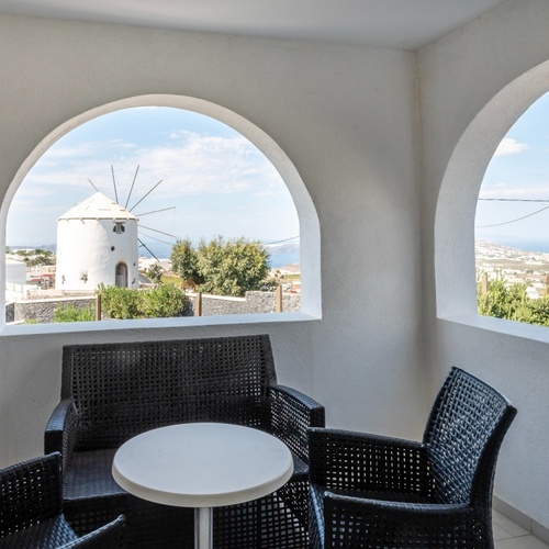 ein Tisch und Stühle auf einem Balkon mit Blick auf eine Windmühle