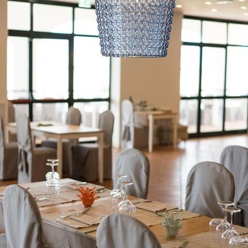 ein Esszimmer mit Tischen und Stühlen und einem blauen Kronleuchter