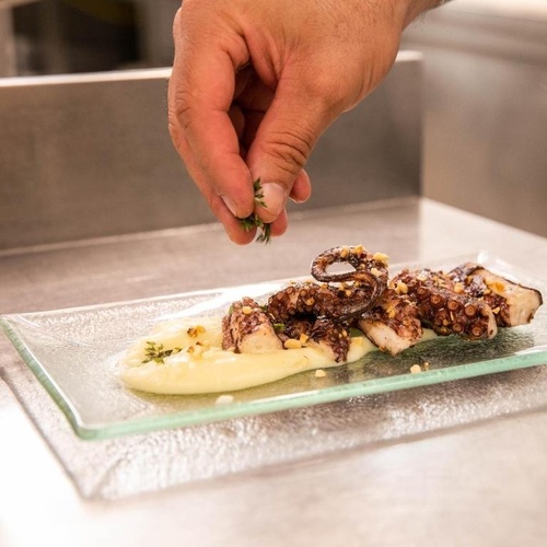 Eine Person streut Kräuter auf einen Teller mit Essen