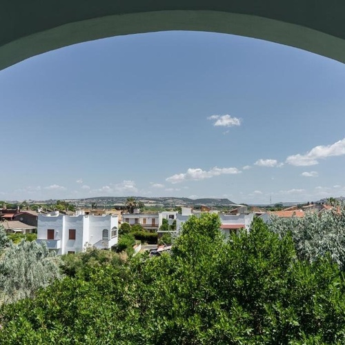 ein Blick auf ein Dorf mit Bäumen und Häusern durch einen Bogen