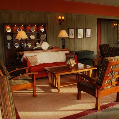a living room with a couch and chairs and a shelf with plates on it