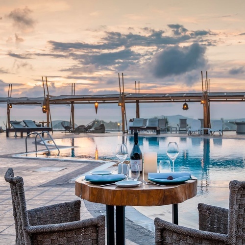 ein Tisch mit zwei Stühlen und einer Flasche Wein neben einem Pool