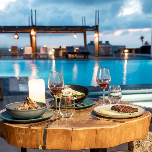 ein Tisch mit Essen und Wein in der Nähe eines Pools