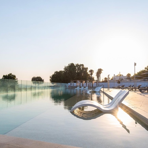 a large swimming pool surrounded by chairs and umbrellas