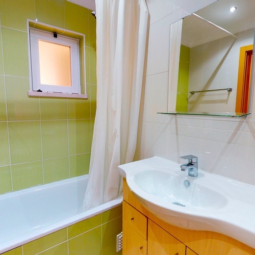 a bathroom with green tiles and a sink