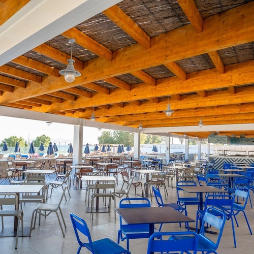 a restaurant with tables and chairs under a wooden roof