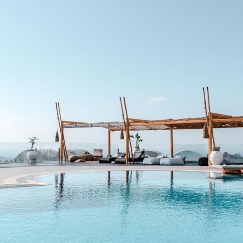 ein großer Swimmingpool mit Liegestühlen und Pergolas umgeben