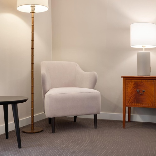 a bedroom with a chair a lamp and a nightstand