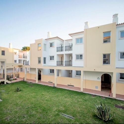 a row of apartment buildings with a lush green lawn in front of them