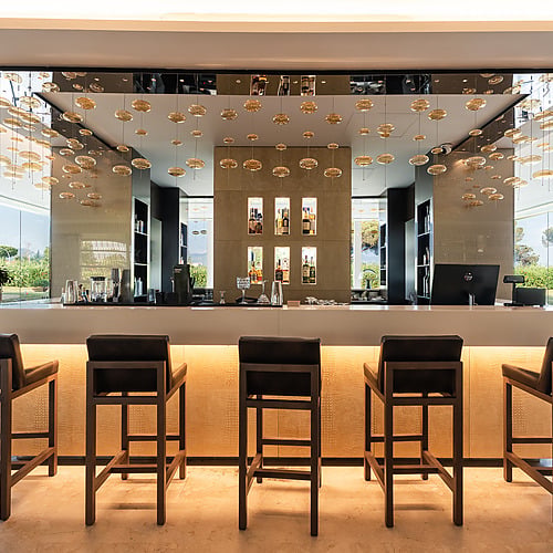 Bar de luxe de l'hôtel avec tabourets, lumières et vue sur jardin. Découvrez notre Smy: Corporativa.