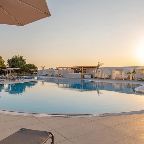 a large swimming pool surrounded by chairs and umbrellas