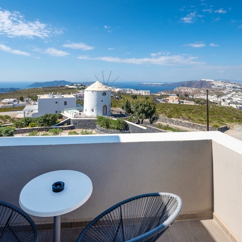 ein Tisch und Stühle auf einem Balkon mit einer Windmühle im Hintergrund