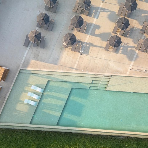 an aerial view of a swimming pool with chairs and umbrellas