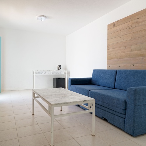 ein Wohnzimmer mit einer blauen Couch und einem weißen Tisch