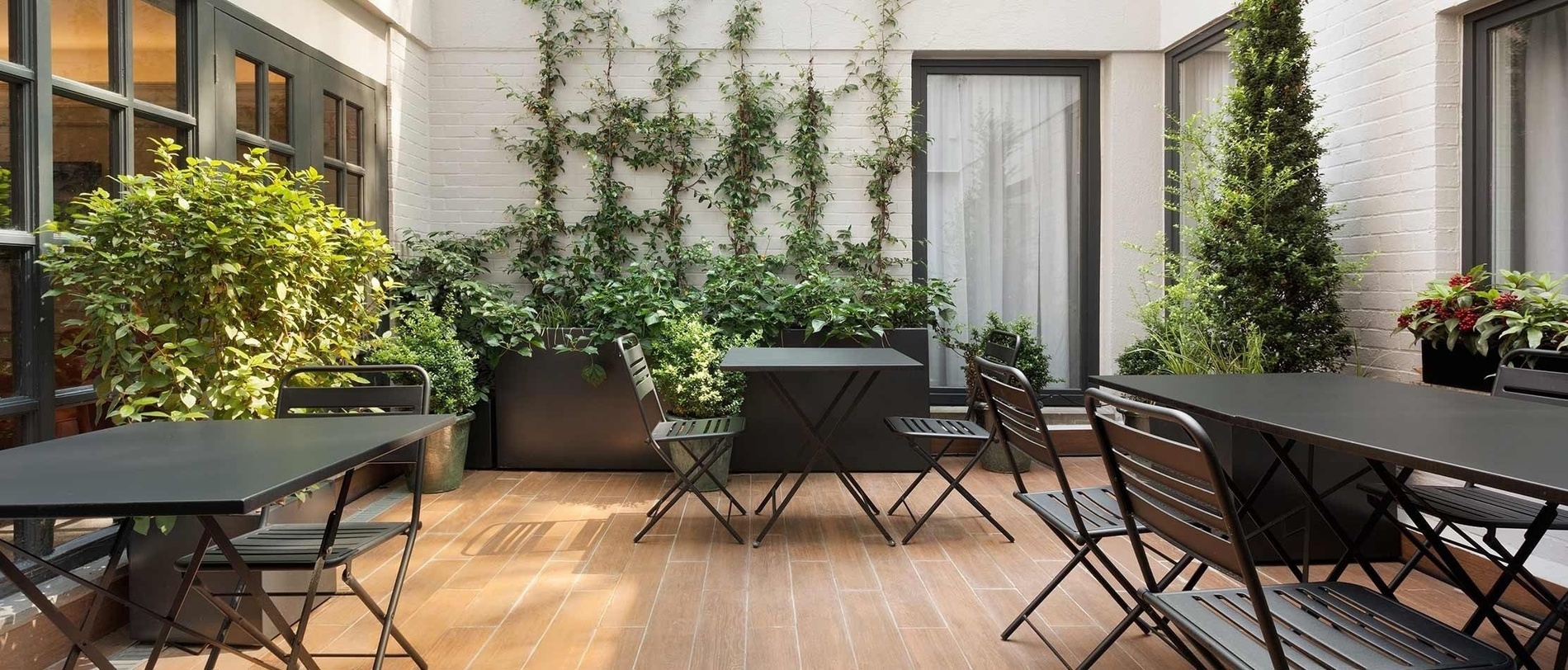 a patio with tables and chairs surrounded by potted plants