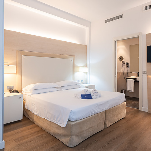 Chambre d'hôtel avec bureau, chaise rouge et lampe, parfaite pour le travail d'entreprise.