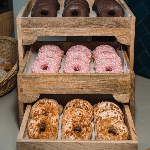 Donuts para eventos corporativos: chocolate, morango e canela em expositor de madeira.
