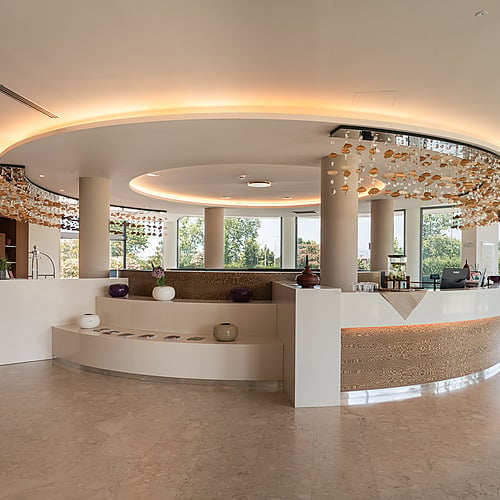 Réception moderne d'un hôtel : comptoir blanc, éclairage d'ambiance, décorations aériennes, vue sur jardin. Smy: Corporativa