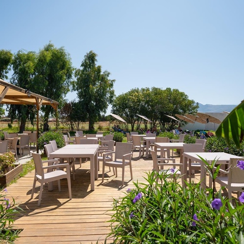 tables and chairs on a wooden deck with purple flowers