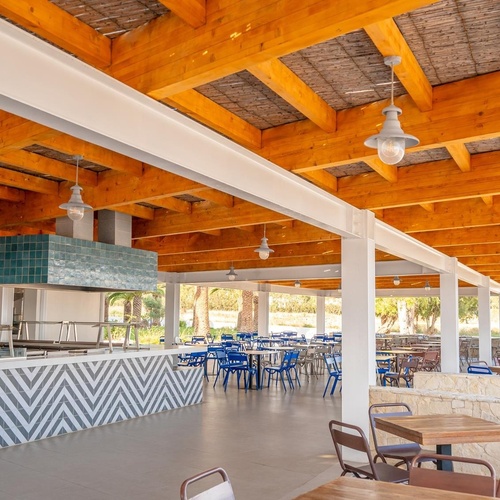 a restaurant with tables and chairs under a wooden roof