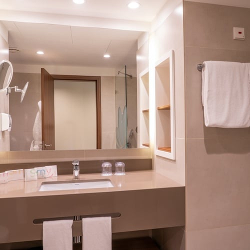 a bathroom with a sink and a mirror with a red button on the wall