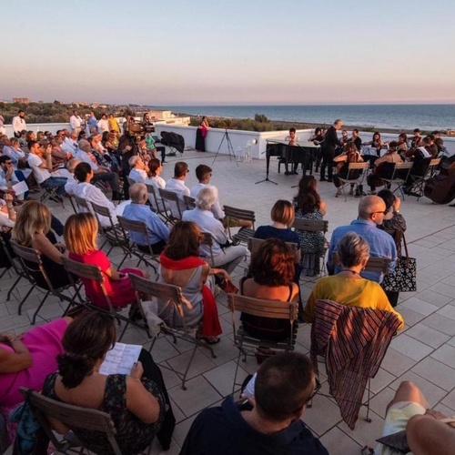 eine Gruppe von Menschen sitzt vor einem Orchester auf einem Dach