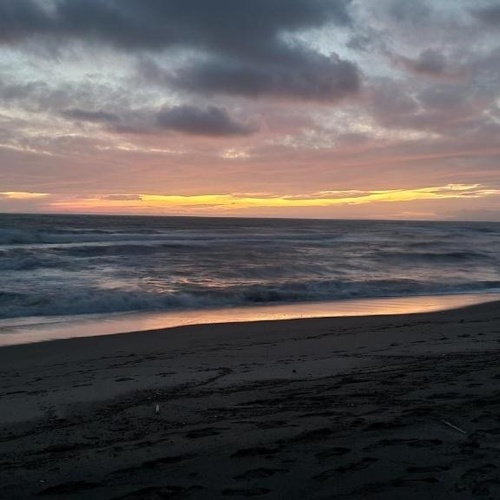 ein Strand mit einem Sonnenuntergang im Hintergrund