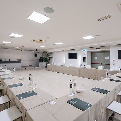 Salle de conférence avec tables en U, chaises et projecteur. Idéal pour vos réunions et événements. Smy: Corporativa