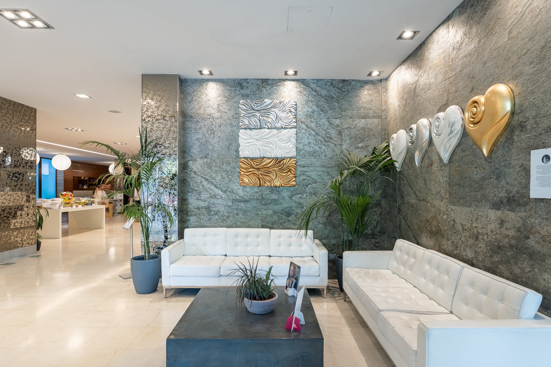 Luxury hotel lobby with modern art, plush sofas, and reflective walls. Smy Bologna Centrale 4 stars | Hotel in Bologna