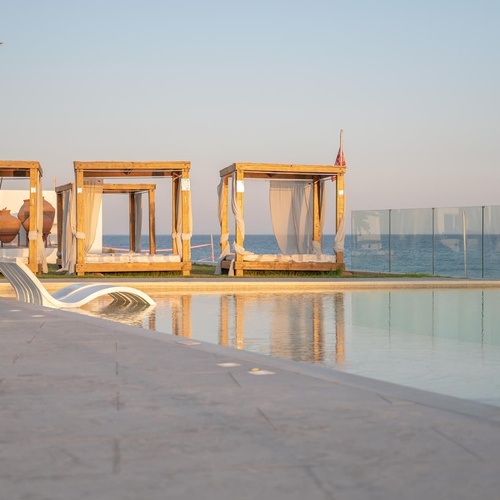 a man sits in a canopy bed next to a swimming pool