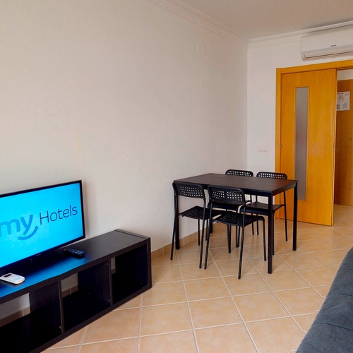 a room with a table and chairs and a tv that says smv hotels