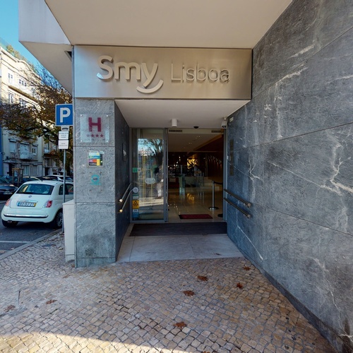 a small white car is parked in front of a building that says smv lisboa