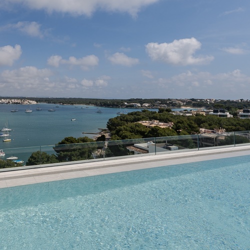 Piscina infinita com vista panorâmica para o mar e marina. Smy: Corporativa.