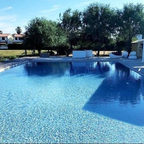 ein großer Swimmingpool mit einem weißen Gebäude im Hintergrund .