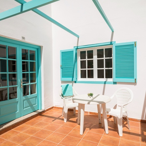 eine Terrasse mit einem Tisch und Stühlen und blauen Fensterläden