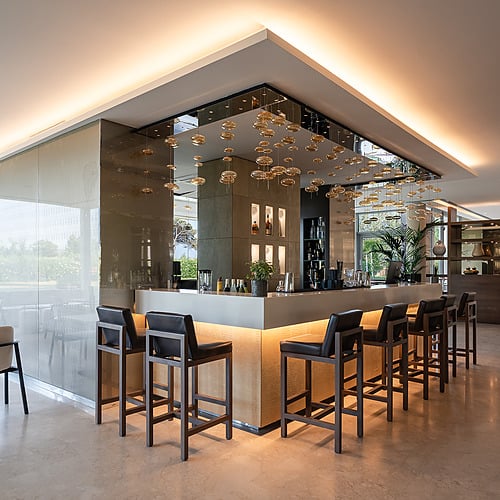 Bar lounge moderne avec chaises hautes, éclairage d'ambiance et vue sur jardin. Idéal pour @Smy: Corporativa.