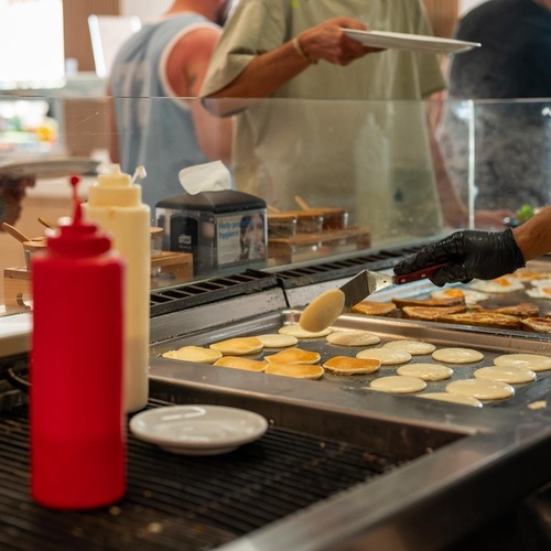 a bottle of tabasco sits on a counter next to pancakes