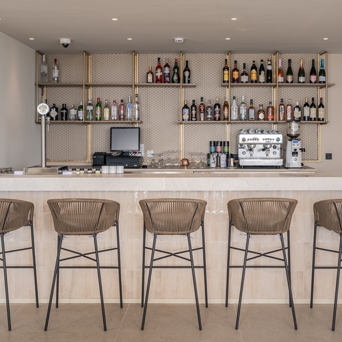 Bar corporativo de hotel moderno com bancos e prateleiras de bebidas.