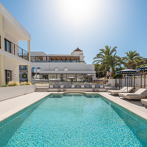 Smy: Corporativa pool and loungers with palm trees and modern hotel.