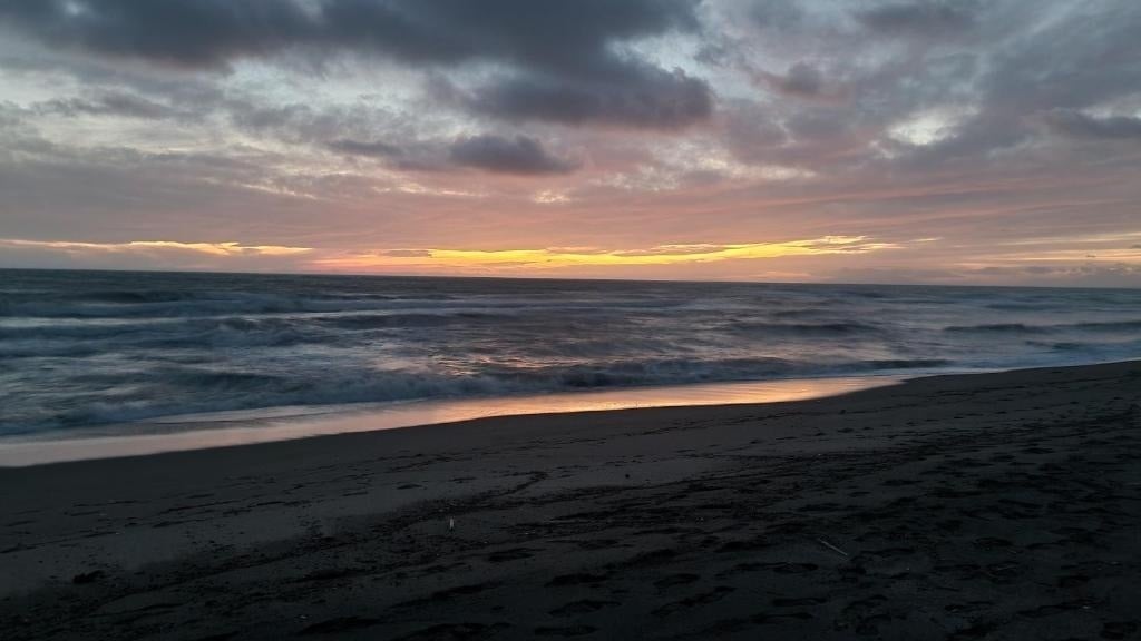 une plage au coucher du soleil avec un ciel nuageux