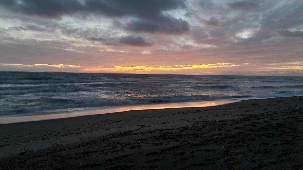 ein Strand mit einem Sonnenuntergang im Hintergrund