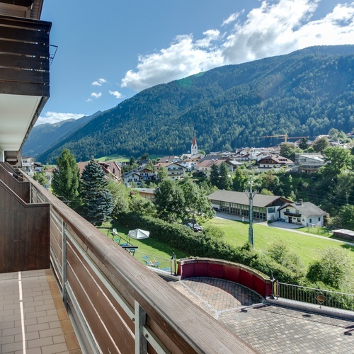 a balcony overlooking a small town with mountains in the background